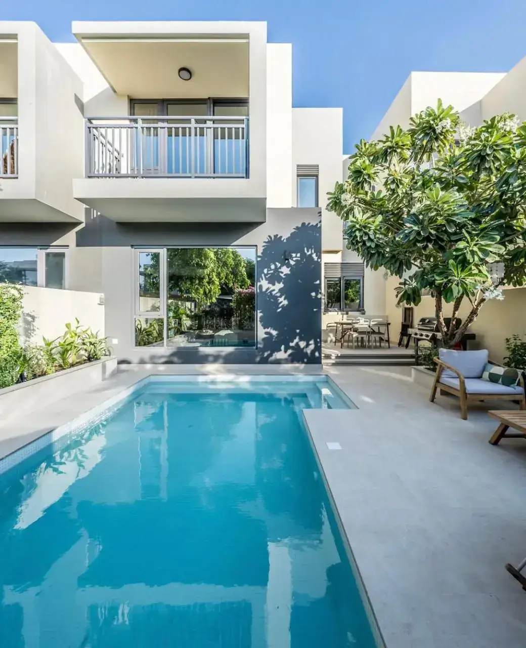 Modern villa swimming pool design in Dubai with contemporary paving, tropical landscaping, and outdoor seating. Designed and constructed by Reshape Landscaping and Design, a British-owned landscaping company in Dubai, UAE, specialising in bespoke pool design and modern outdoor spaces.