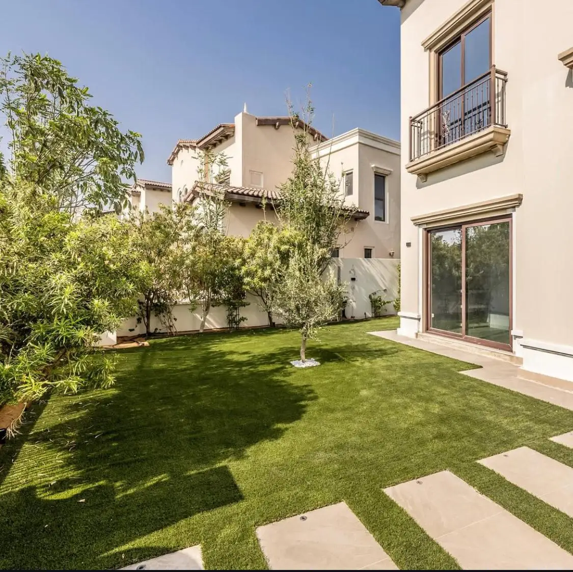 Artificial grass landscaping in Dubai villa garden with natural tree planting and stepping stone pathway