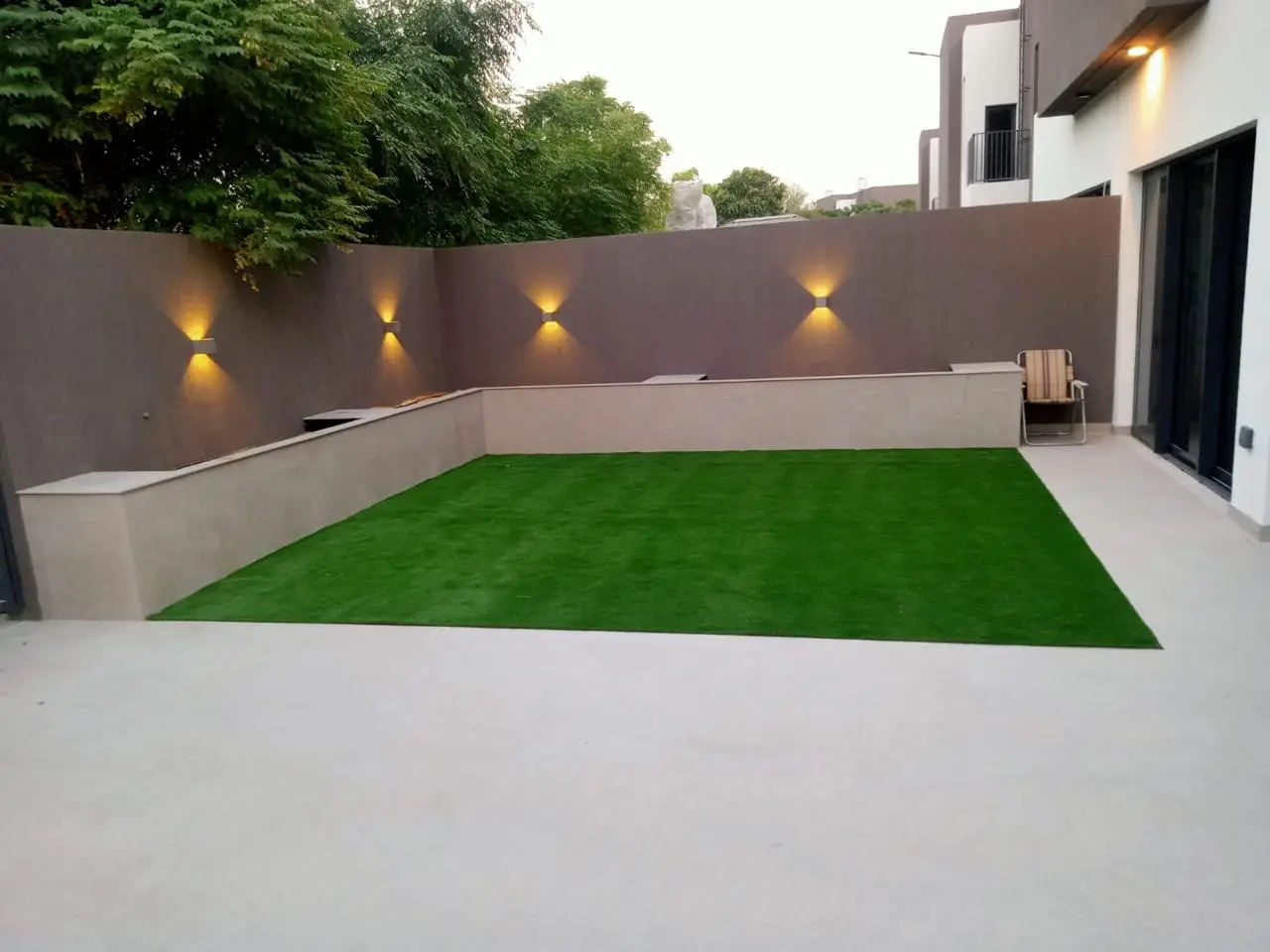 Minimalist backyard with artificial lawn and feature lighting – Arabian Ranches landscape renovation by Reshape Landscaping and Design