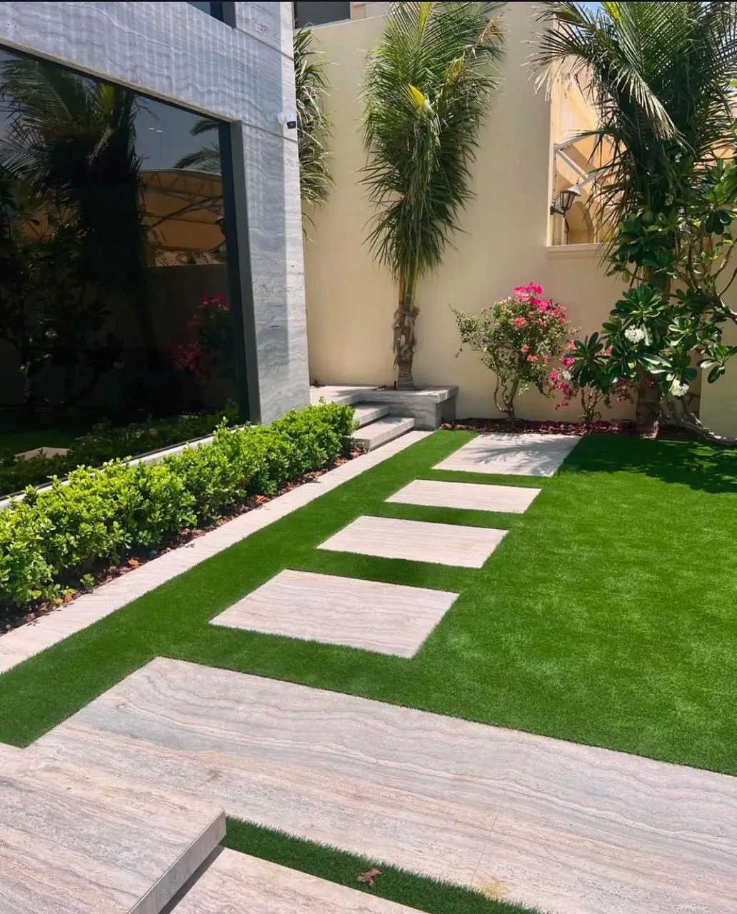 Artificial grass installation in Dubai villa with modern stepping stone pathway and tropical planting design