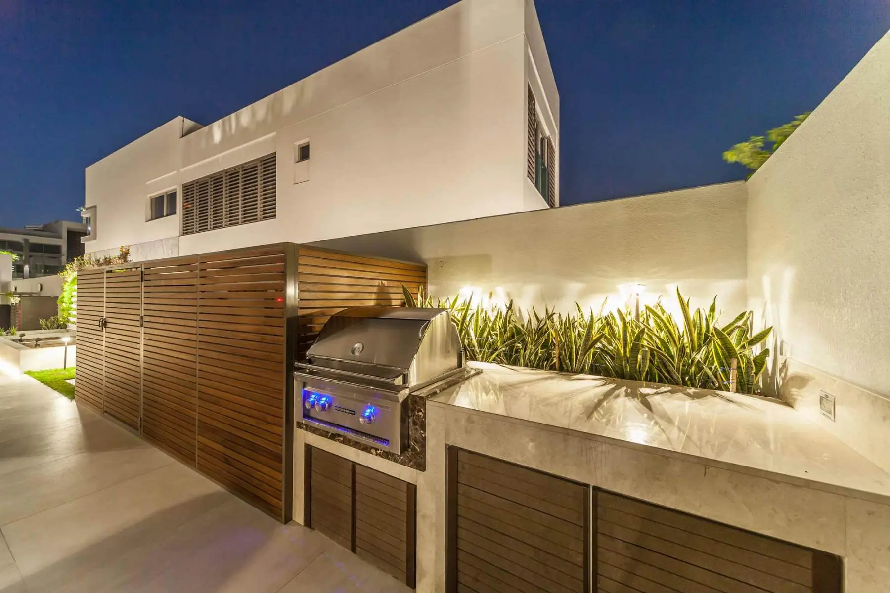 Luxury outdoor kitchen and landscaping design in Dubai villa with built in BBQ, modern hardscape and garden lighting