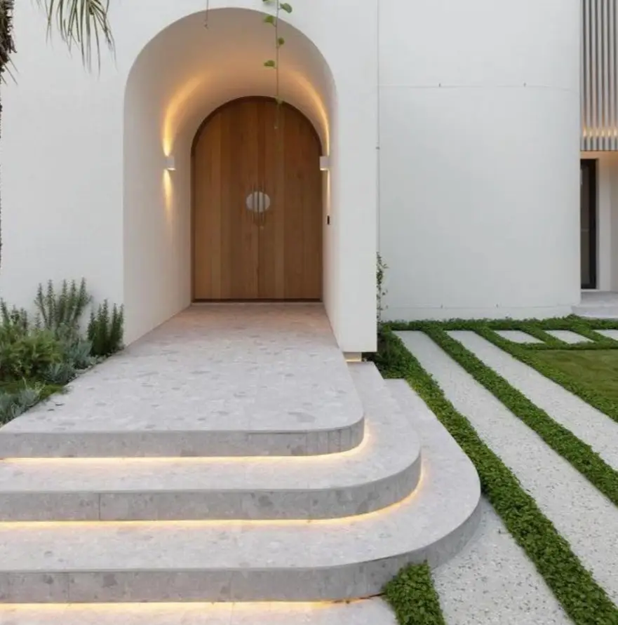 Modern house entrance with curved stone steps, recessed lighting and minimalist planting